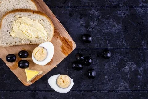 Top view boiled egg on a board with olives and slices of bread and butter o.. Stock Photos