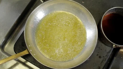 Top view of boiling butter on a hot metal frying pan. Stove surface in kitchen Stock Footage 88673104
