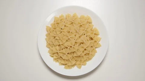 TOP VIEW: Bow noodles appear on a white dish on a white table (stop motion) 動画素材 69809213