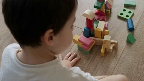 Top view of a boy building tower of block toys sitting on the floor at home Stock Footage 194460412