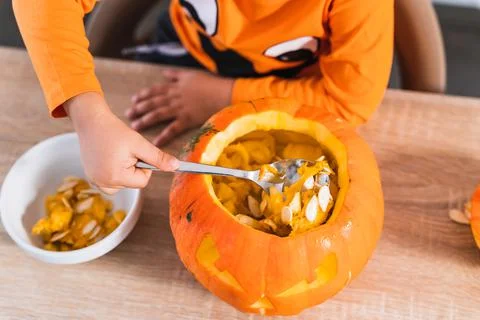 Top view of a boy dressed as a halloween pumpkin emptying a pumpkin to decorate Stock Photos
