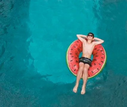 Top view of boy floating on inflatable watermelon float in a pool. Stock Photos