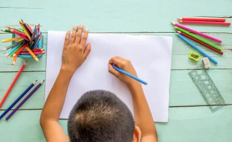 The top view of the boy uses colored pencils to draw on white paper. Foto stock