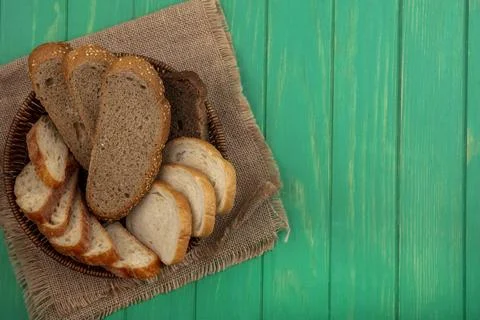 Top view of breads as seeded brown cob and baguette slices in basket on sac.. Stock Photos