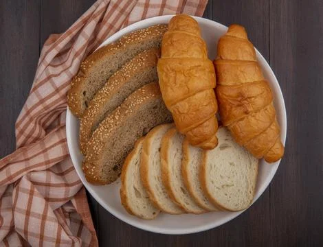 Top view of breads as sliced seeded brown cob baguette and croissants in pl.. Stock Photos