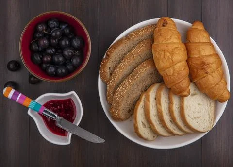 Top view of breads as sliced seeded brown cob baguette and croissants in pl.. Stock Photos