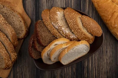 Top view of breads as sliced seeded brown cob rye and white ones in bowl an.. Stock Photos
