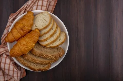 Top view of breads as sliced seeded brown cob baguette and croissants in pl.. Stock Photos