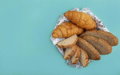 Top view of breads as sliced seeded cob baguette and croissant in bowl on b.. Stock Photos