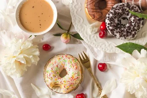 Top view of breakfast in bed with various delicious glazed donuts on the plate Stock Photos