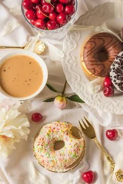 Top view of breakfast in bed with various delicious glazed donuts on the plate Stock Photos