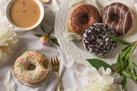 Top view of breakfast in bed with various delicious glazed donuts on the plate Stock Photos
