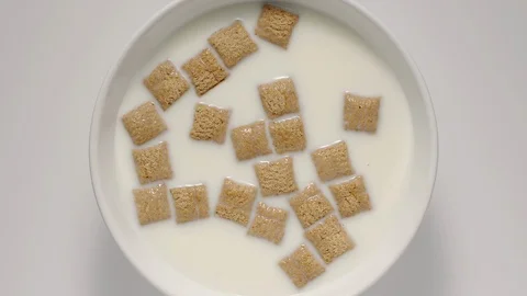 TOP VIEW: Breakfast cereal bites and milk in a white bowl on the table Vídeo Stock 108573497