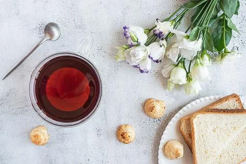 Top view of a breakfast with a cup of tea, cookies, bread and flowers Stock Photos