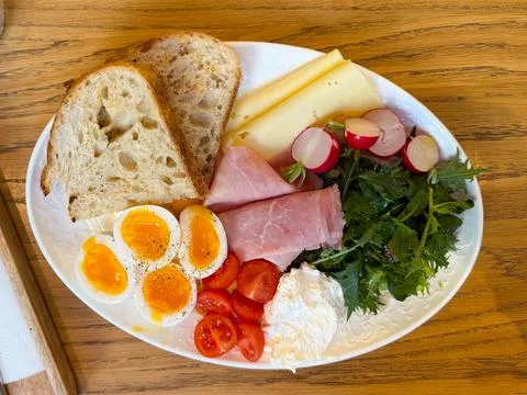 Top view breakfast plate with eggs bread cheese ham and fresh vegetables on w Stock Photos