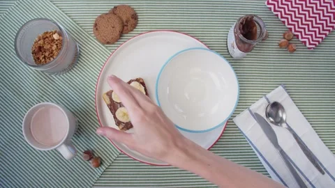 Top view breakfast preparation, women's hands pour granola into plate and pour Stock Footage 138099308