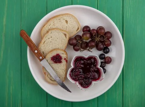 Top view of breakfast set with bread slices raspberry jam and grape with kn.. Stock Photos