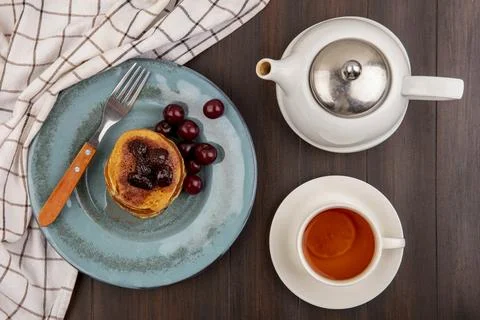 Top view of breakfast set with pancake and cherries and fork in plate on pl.. Stock Photos