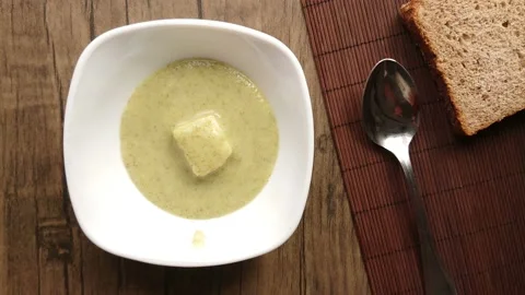 Top view of the broccoli cream soup poured on feta cheese cube into white bowl Stock Footage 233844008