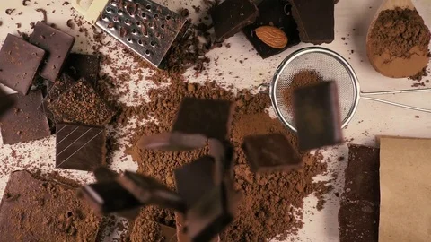 Top view. Broken chocolate falls down on cocoa powder. Slow motion Stock Footage 75186702