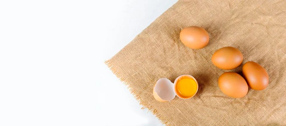 Top view broken raw egg with the yolk and albumen on a linen tablecloth on wh Stock Photos
