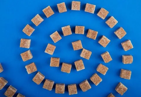 Top view of brown sugar cubes arranged on blue background Stock Photos