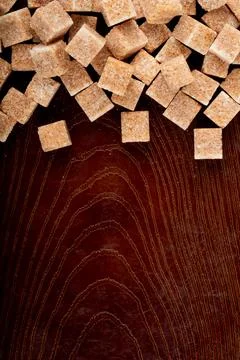 Top view of brown sugar cubes scattered on wooden background with copy space Stock Photos