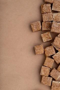 Top view of brown sugar cubes arranged on brown paper texture background wi.. Stock Photos