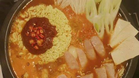 Top view of bubbling Budae Jjigae with instant noodles, slow motion Stock Footage 338242229