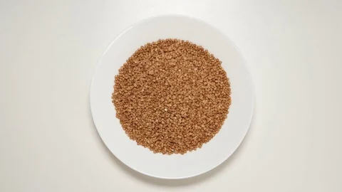 TOP VIEW: Buckwheats fill a white dish (stop motion) Stock Footage 69809216