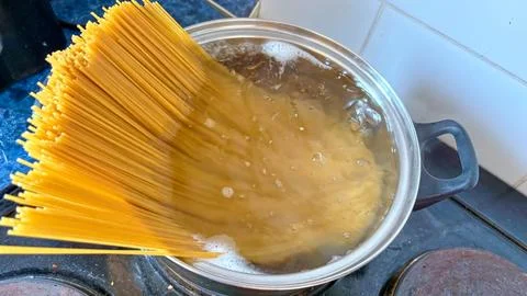 Top view of a bunch of dry spaghetti immersed in a pot of hot boiling water and Stock Photos