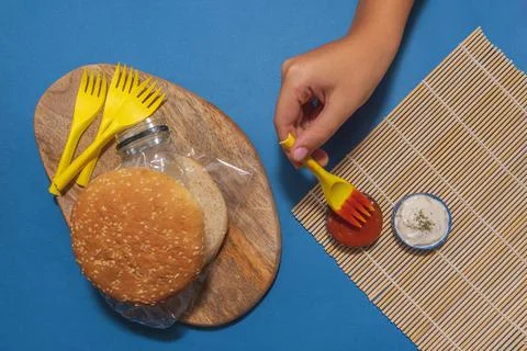 A top view of a burger with plastic in it and a hand next to it - pollution c Foto stock
