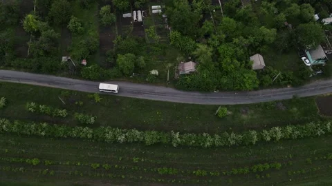 Top view of a bus driving on a dirt road near small houses Stock Footage 166362086