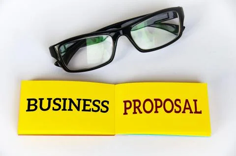 Top view of business proposal text on yellow notepad with glasses on white .. Stock Photos