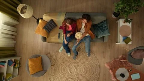 Top view capturing a young couple sitting on the couch and watching a movie Stock Photos