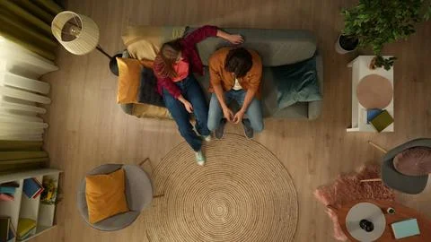 Top view capturing a young couple sitting on the couch together. The man seems Stock Photos