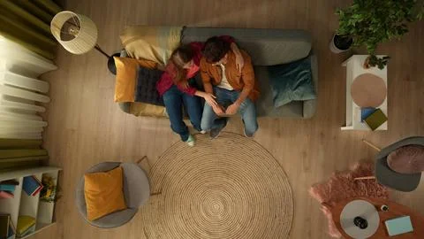 Top view capturing a young couple sitting on the couch together. The man seems Stock Photos