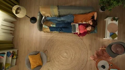 Top view capturing a young couple laying on the couch, cuddling and talking Stock Photos