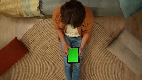 Top view capturing a young man sitting on the floor, looking at the tablet Stock Photos
