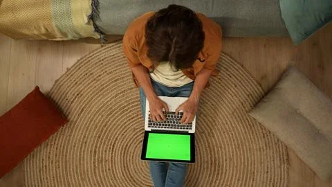 Top view capturing a young man sitting on the floor, looking at the laptop Stock Photos