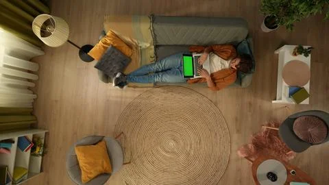 Top view capturing a young man laying on the couch, looking at the laptop screen Stock Photos
