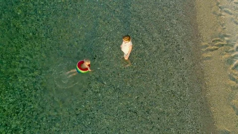 Top view caring mother helping little son swimming using lifebuoy in clear sea Stock Footage 98608484