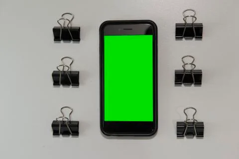 Top view of cell phone surrounded by paper clips. Stock Photos