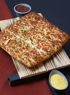Top view of cheesy rectangular pizza served with sauces on a wooden tray Stock Photos