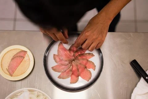 Top View of Chef Hands Arranging Sliced Roast Beef Carpaccio on Plate Stock-Fotos
