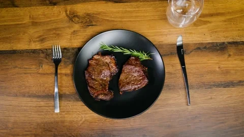 Top View. The chef serves baked juicy beef steak sprinkled with seasoning Stock Footage 188554219
