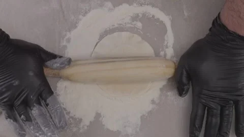 Top view of chef's hands in gloves rolling out circles with rolling pin. Stock Footage 313973044