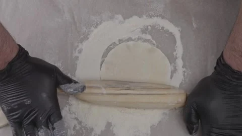 Top view of chef's hands in gloves rolling out circles with rolling pin. Stock Footage 316512661