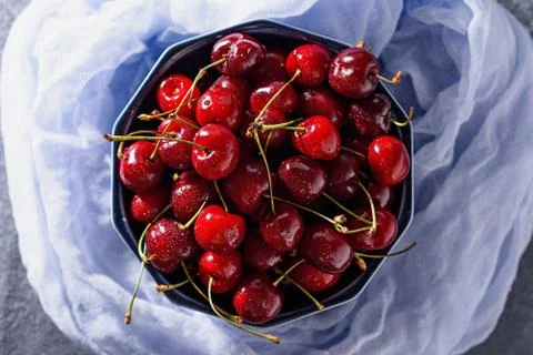 Top view cherries with drop in blue bowl on blue gauze Stock Photos