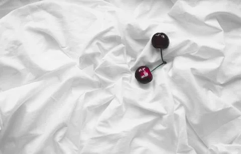 Top view of a cherry on a crumpled white background of bed linen. Stock Photos